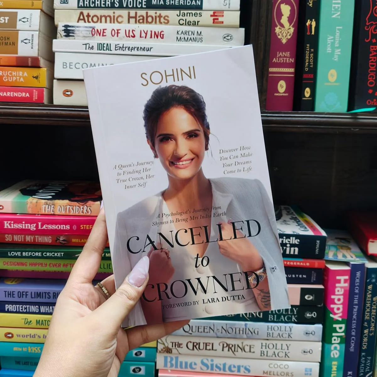 A hand holding Cancelled to Crowned in a bookshop